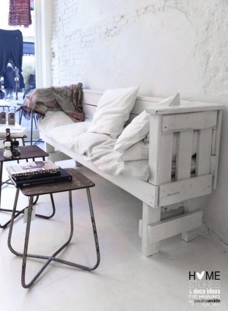 Biała ławka z drewnianej palety, industrialne stołki metalowe i biała cegła z patyna na ścianie
