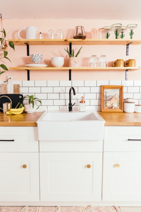 Białe szafki z drewnianym blatem w pastelowej kuchni