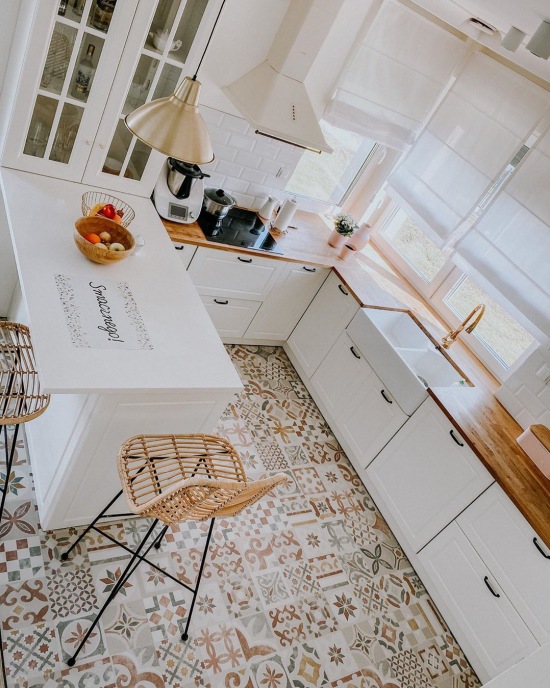 Wzorzysta podłoga w kuchni z białymi szafkami i drewnianym blatem