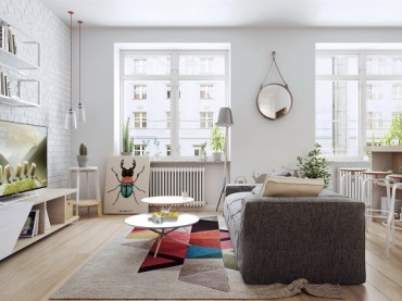 Szara sofa w salonie oraz dominująca biel wyznaczają spokojny styl skandynawski. Przestrzeń znacząco urozmaicają jednak...