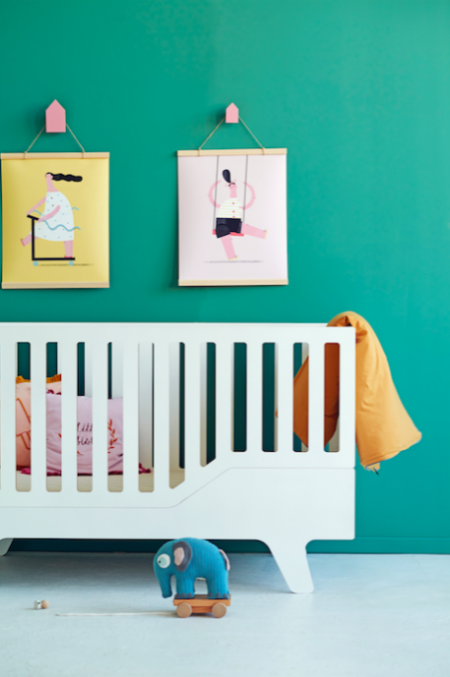 Pokoik dziecięcy ze szmaragdową ścianą i białym łóżeczkiem