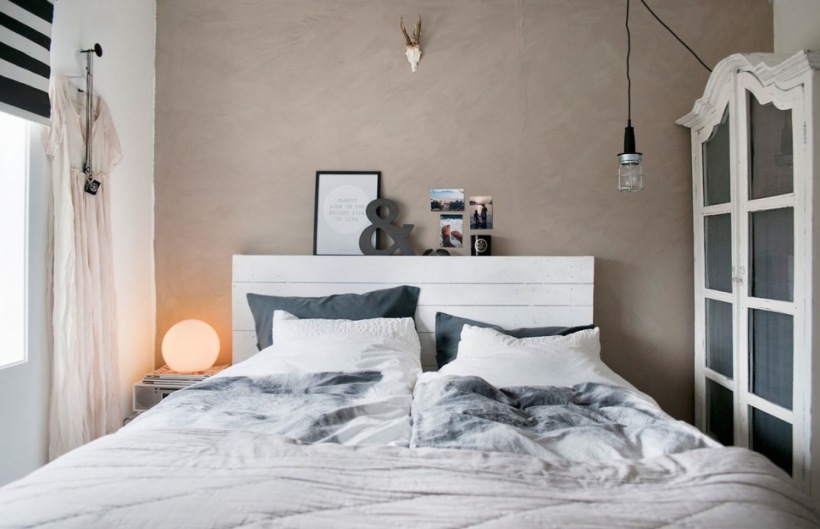 Beton dekoracyjny na ścianie w sypialni,biała serwantka szafa,industrialna żarówka na kablu,białe łóżko