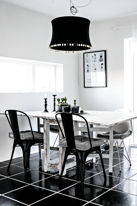 Biała jadalnia z czarną lampą , krzesłami i podłogą