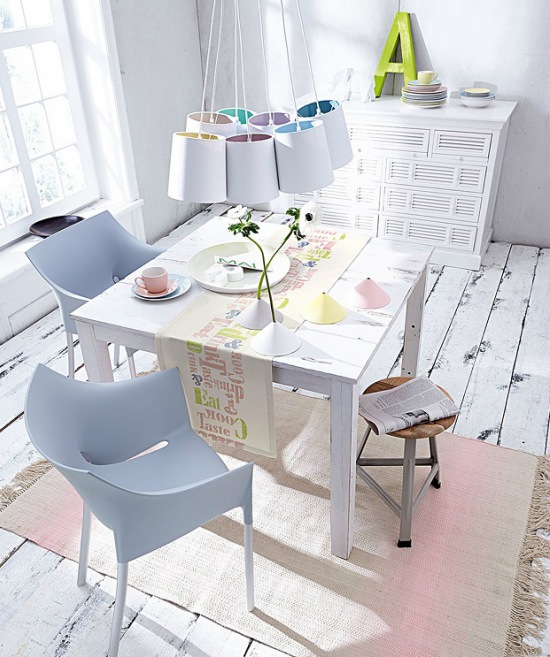 Nowoczesne krzesła z tworzywa,biały stół,podłoga bielona vintage i kolorowe wnętrza abażurów w lampie wiszącej nad stołem w jadalni
