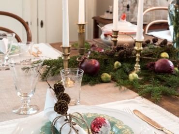 Złote świeczniki i elegancka zastawa stołowa potęgują odświętną aurę, jaka panuje w jadalni. Zielone gałązki świerku...