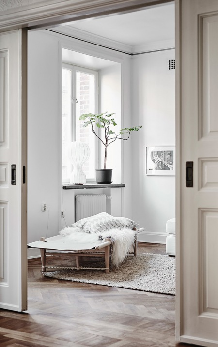 Białe wnętrza skandynawskiego domu z przesuwnymi drzwiami,drewnianą ławką leżanką