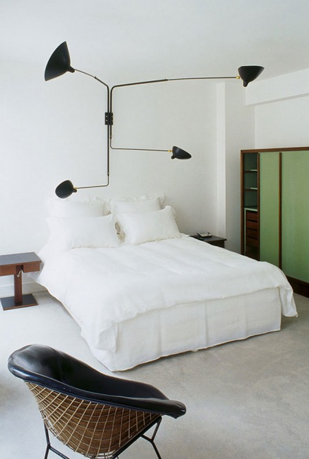 Oryginalna, czarna  lampa ścienna z czterema ramionami nad łóżkiem