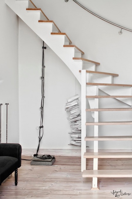 Białe schody z drewnianymi stopnicami i żarówki na kablu w aranżacji wnętrz w stylu skandynawskim
