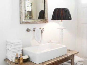 W łazience zastosowano sporo dekoracji, w tym lustro w postarzanej ramie oraz drewniany stolik pod umywalką. Jednym z...
