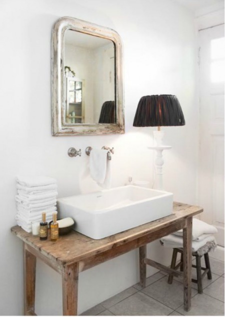 Lustro i drewniany stolik w aranżacji łazienki