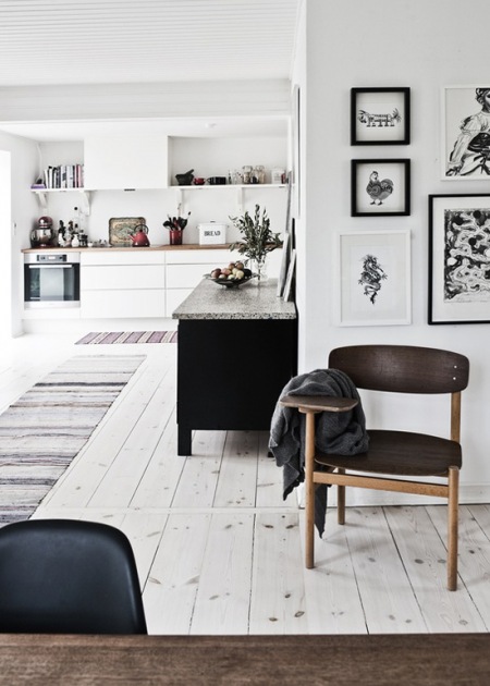 Drewniane krzesła,czarna komoda i biało-czarne grafiki w skandynawskiej aranżacji