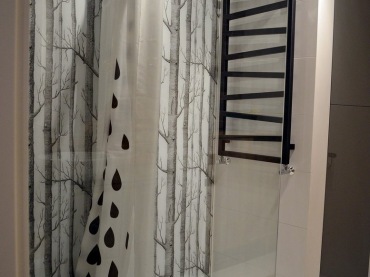 W strefie prysznicowej na ścianie położono szklany panel z nadrukiem nawiązującym do salonowej tapety. Motyw drzew...