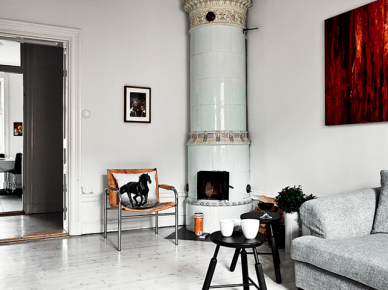Skandynawski bialy salon z ceramicznym piecem, szarą sofą,i nowoczesnym obraze, w brązach (21081)