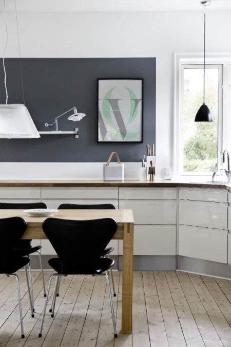 Biała kuchnia z czarną ścianą i krzesłami i drewniana naturalna podłoga z desek