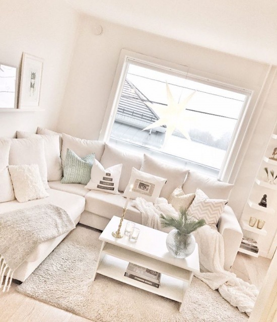 Biały salon z narożną sofą i dekoracją z gwiazdy w oknie