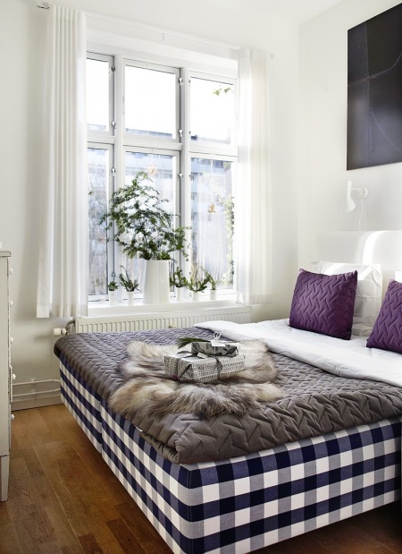 Sypialnia z łóżkiem z tapicerką w kratkę i naturalna dekoracją świąteczną okna