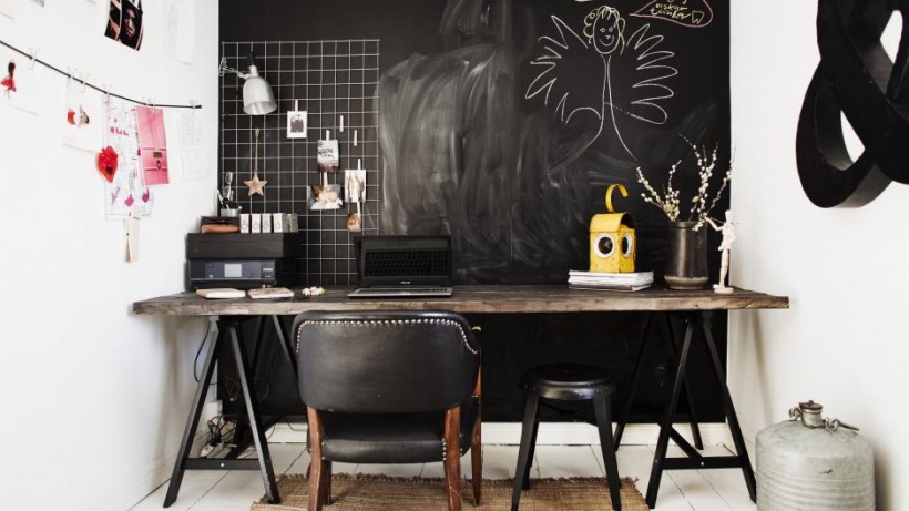 Skandynawskie biurko z postarzanym drewnianym blatem na czarnych kozłach,czarna ściana z tablicową farbą,czarne krzesło na drewnianych nogach,czarny stołek industrialny