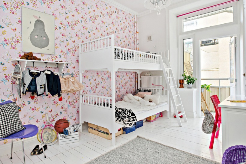 Różowa tapeta w kwiatki w pokoju dziecięcym,biała podłoga z desek,białe łóżka pietrowe z drewna dla dzieci,fioletowe dodatki