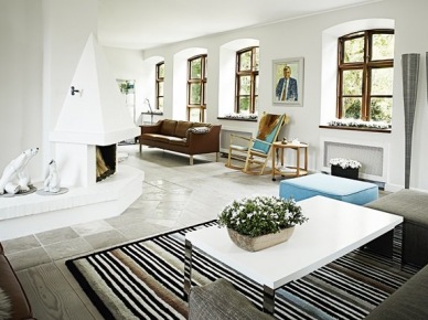 Biały salon z kominkiem,kamienną nowoczesna podłogą,skórzaną sofą i nowoczesnym stolikiem na pasiastym dywanie (25038)