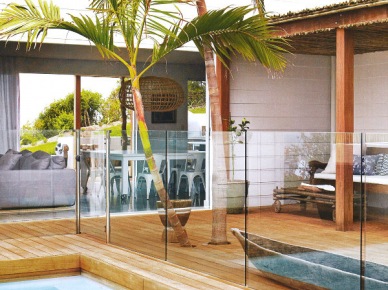 Szklana balustrada wokół basenu,drewniane deski na tarasie z rustykalnym dachem pośród egzotycznych palm (25141)