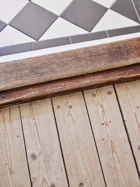 Łączenie drewnianej podłogi z desek z biało-czarna terakotą ułożoną w karo