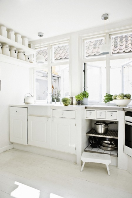 Białe pojemniki z porcelany, biała podłoga i białe szafki  w wiejskiej kuchni skandynawskiej