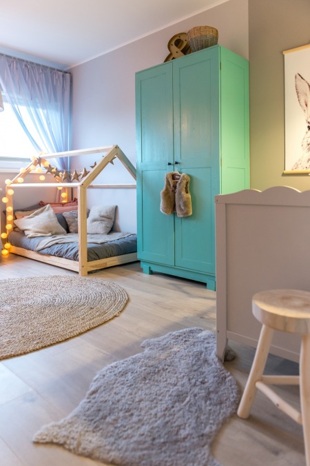 Niebieska szafa i łóżko-domek w pokoju dziecięcym