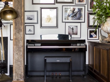 W salonie jedną ze ścian niemal w całości przeznaczono na sporą galerię złożoną z rodzinnych fotografii. Znalazło się tu także czarne pianino, które wygląda zupełnie niepozornie wśród tak bogatej aranżacji...