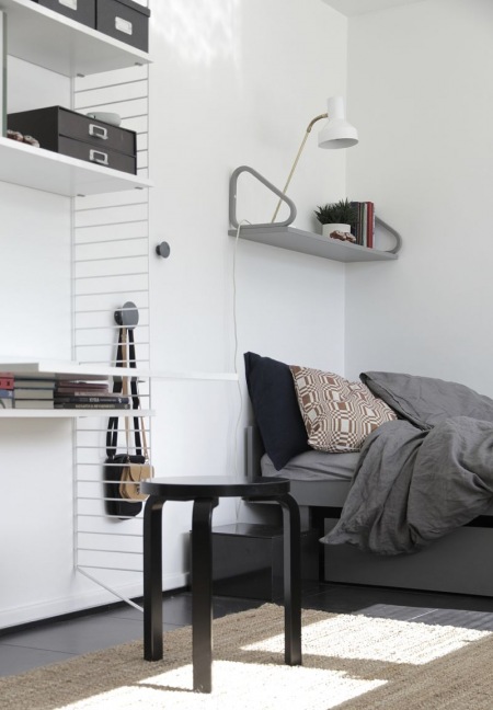 Aranżacja biało-szarej sypialni z metalowymi półkami w stylu skandynawskim