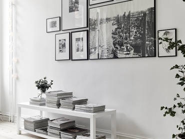 Biała niska konsolka z pólkami w salonie z białymi ścianami,galeria nowoczesnych fotografii w czarnych wąskich ramkach na ścianie (48132)