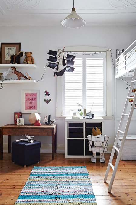 Drewniane biurko vinate,białe półki,piętrowe łózka z drabinką i sznurkowy dywan niebieski w dzieciecym pokoju