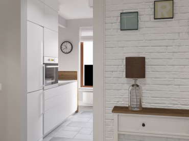 Białe mieszkanie urozmaicone jest elementami ciemnego drewna, przez co wizualnie zyskuje na wyrazistości. Jasne szafki w kuchni czy białe cegły w przedpokoju podkreślają skandynawski styl...