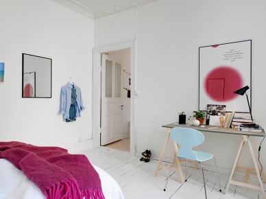 Rózowy pled z frędzlami,plakat z rózowym akcentem i niebieskie krzesło w białej sypialni (24606)