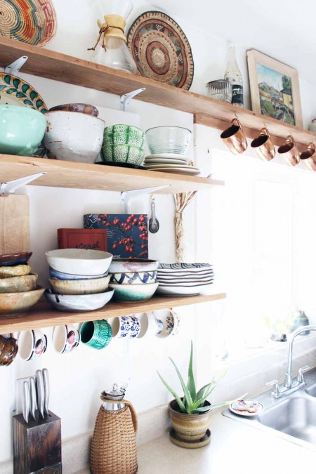 Kolorowe naczynia i dodatki na drewnianych półkach w kuchni