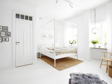 Białe nowoczesne  łóżko z wysokimi ramami i beżową narzutą  , jasnobrązowy dywan i mała galeria fotografii na ścianie (24667)