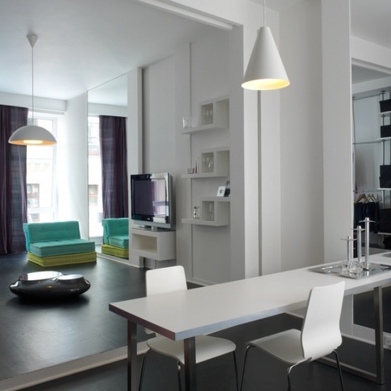 Biały nowoczesny salon z turkusowymi fotelami w otwartej zabudowie mieszkania