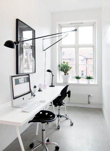 Czarny kinkiet na wysięgniku z przgubami,czarne nowoczesne krzesła biurkowe,białe i wąskie podwójne biurko w stylu skandynawskim