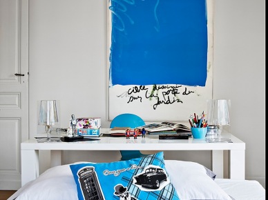Nowoczesny obraz z niebieskim motywem,niebieska poduszka i detale w białej sypialni z biurkiem (25398)
