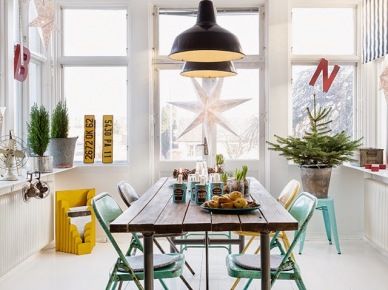 Biała szwedzka jadalnia z czarnymi industrialnymi lampami nad metalowym stołem z drewnianym blatem, turkusowe metalowe krzesła i żółte dodatki w dekoracji białego wnętrza (27524)