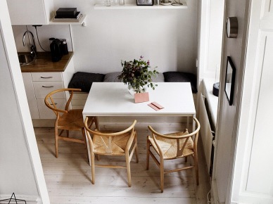 Biały nowoczesny stół w jadalni przy kuchni z zabudowanymi siedziskami i drewnianymi skandynawskimi krzesłami z plecioną jutą (27651)