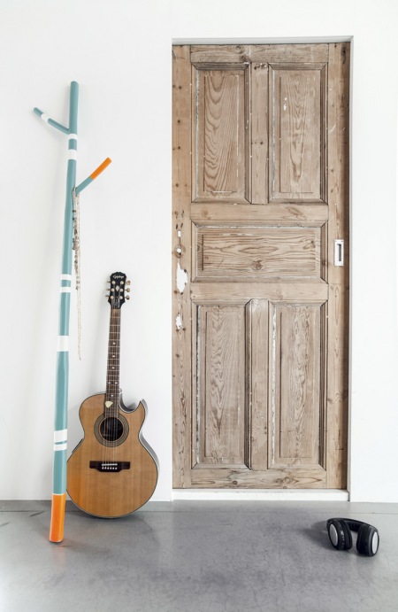 Drzwi z naturalnego drewna ,niebieski wieszak i betonowa podłoga w skandynawskiej aranżacji