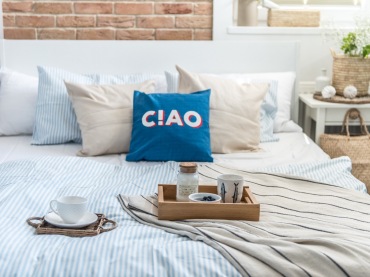 W aranżacji małej sypialni jest jeden element, który się wyróżnia. To niebieska poduszka z napisem, która sprawdza się...