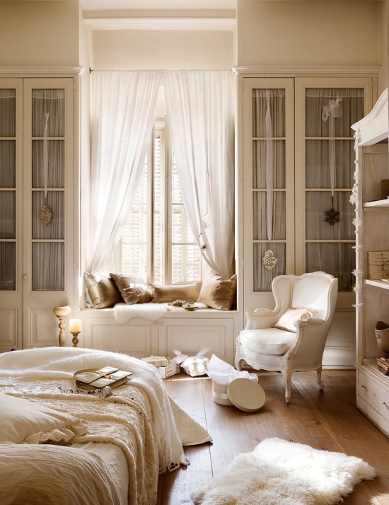 Prowansalska pastelowa sypialnia z fotelem, zabudowanymi przeszklonymi szafami i siedziskiem przy oknie