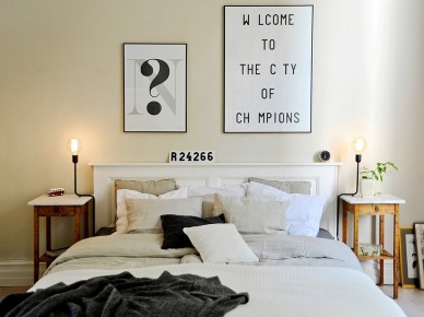 Typografie i grafiki na ścianie w skandynawskiej sypialni z białym łóżkiem i stylowymi drewnianymi stolikami nocnymi (23453)