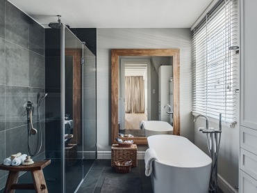 Elegancką łazienkę urozmaicają drewniane i wiklinowe dodatki, wśród których najbardziej wyróżnia się duże lustro w...