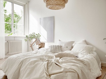 Aranżacja sypialni jest bardzo naturalna i świeża. Niemal wszystko, łącznie z pościelą, wybrano w białym kolorze, co dodatkowo rozświetla niewielkie wnętrze. Wiklinowy kosz od lampy oraz drewniana podłoga potęgują wrażenie...