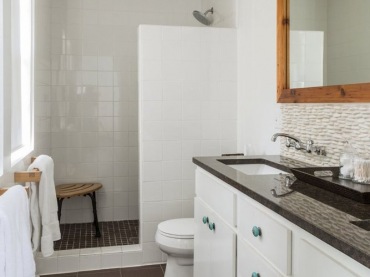 Higienicznie biała łazienka ocieplona drewnianą ramą lustra i brązową podłogą oraz blatem w takim samym kolorze. Duża...
