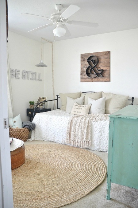 Okragły dywan z juty,czarna kuta ławka,turkusowa komoda i drewniane litery 3D na ścianie