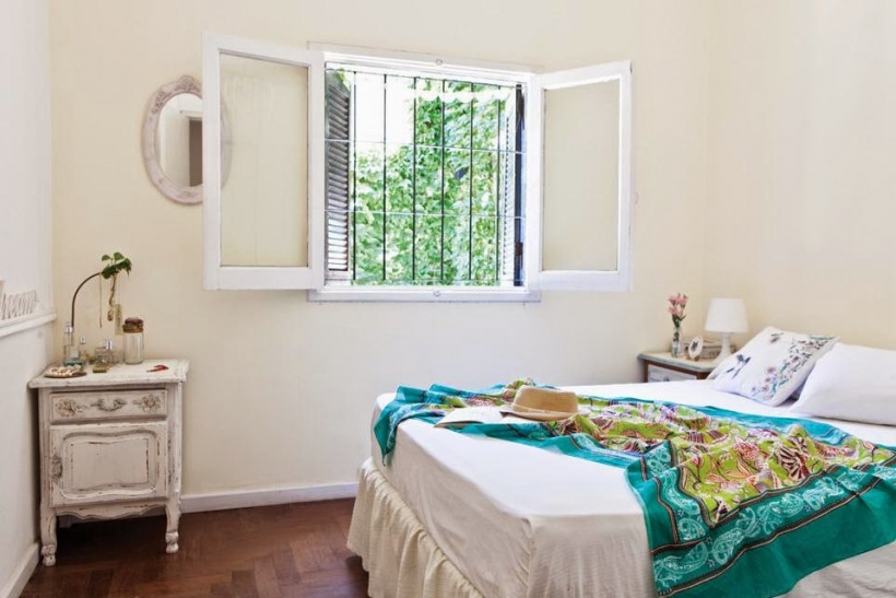 Turkusowa narzuta,stolik bielony vintage i owalne lusterko w białej sypialni