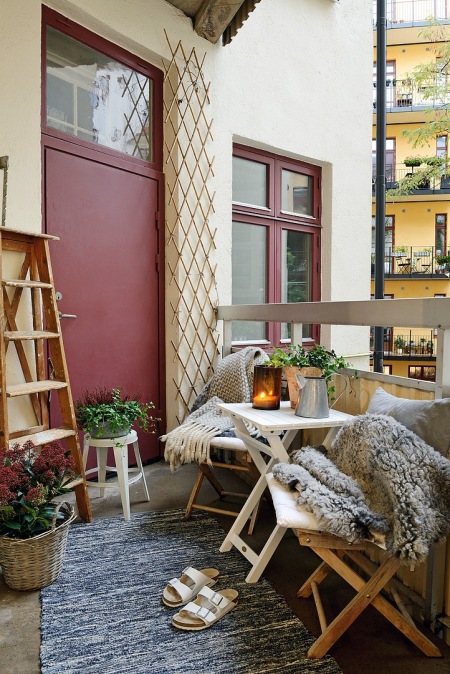 Futrzaki,lampiony,drewniana drabina,ocynkowane konwie i drewniane meble na małym balkonie